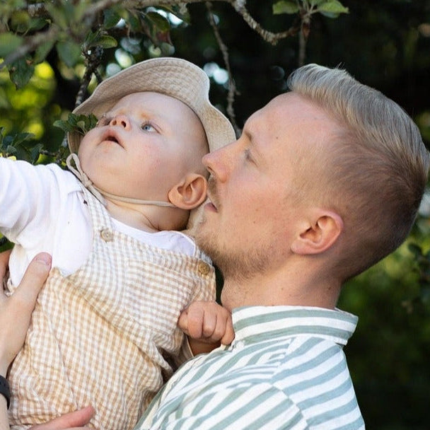 Man holding a baby in front of an apple tree